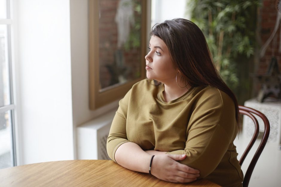 Young woman sitting at a table looking about a window